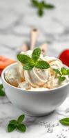 Creamy vanilla ice cream served in a white bowl garnished with fresh mint leaves on a marble countertop photo