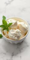 Creamy vanilla ice cream with fresh mint leaves served in a bowl on marble countertop during summer photo