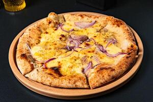 a pizza with onions and onions on it sits on a table. photo