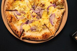 a pizza with onions and onions on it sits on a table. photo