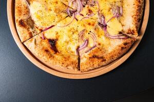a pizza with onions and onions on it sits on a table. photo