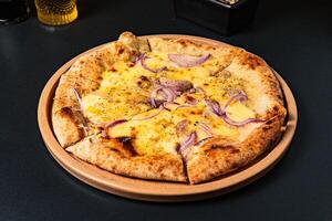 a pizza with onions and onions on it sits on a table. photo