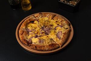 a pizza with onions and onions on it sits on a table. photo