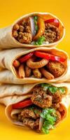 Delicious wraps filled with fried chicken, fresh vegetables, and sauces stacked on a vibrant yellow background photo