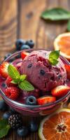 Bright and colorful fruit sorbet topped with fresh berries and mint in a glass bowl on a wooden table photo