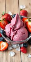 Delicious berry sorbet topped with fresh strawberries and blueberries in a glass bowl on a wooden table photo