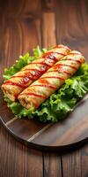 Deliciously rolled crispy snacks topped with sauce on fresh green lettuce served on a wooden platter photo