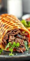 Delicious beef wrap filled with fresh vegetables and herbs served on a black plate photo