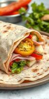 Delicious wrap filled with fresh vegetables and ham served on a plate in a bright setting with herbs in the background photo