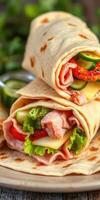Freshly made wraps filled with vegetables and deli meats on a wooden table photo