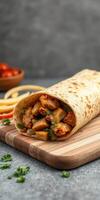 Delicious chicken wrap on a wooden board with fresh cilantro and cherry tomatoes in the background photo