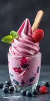 Delicious berry swirl frozen yogurt served in a clear glass topped with fresh fruits photo