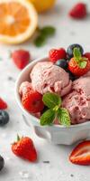 Fresh strawberry and blueberry ice cream served in a white bowl with vibrant fruits and mint leaves on a light surface photo