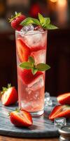 Refreshing strawberry cocktail served with mint leaves and ice on a wooden table photo