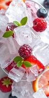 Refreshing summer drink with ice and berries garnished with mint leaves in a clear glass bowl photo