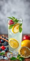 Refreshing summer cocktail garnished with mint and citrus sits on a wooden table surrounded by fresh fruits photo