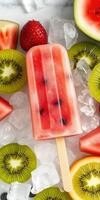 Colorful watermelon popsicle surrounded by fresh fruits and ice on a bright summer day photo