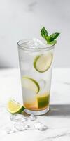 Refreshing lime and mint cocktail served in a tall glass with ice on a marble countertop photo