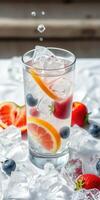 Refreshing summer cocktail with ice and fresh fruit garnished in a clear glass photo