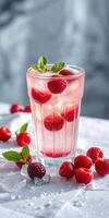 Refreshing raspberry drink garnished with mint in a glass on a white table with scattered berries photo