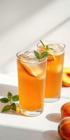 Refreshing iced tea served in transparent glasses with fresh mint and ripe peaches on a sunlit table photo
