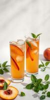 Refreshing summer peach iced tea served in tall glasses with mint leaves and peach slices on a light background photo