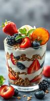 Delicious layered dessert featuring yogurt, granola and fresh fruits served in a glass photo
