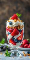 Delicious berry parfait layered with yogurt, granola, and fresh fruits served in a clear glass photo