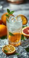 Refreshing citrus drink garnished with mint served in a clear glass with ice cubes alongside fresh oranges photo