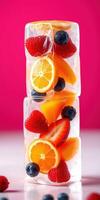 Colorful frozen fruit cubes stacked on a white surface with a vibrant pink background photo