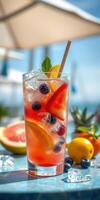 Colorful summer fruit drink garnished with mint served by the beach during a sunny afternoon photo