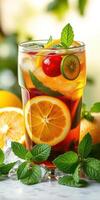 Refreshing fruit cocktail served in a tall glass with ice and fresh mint on a sunny day photo