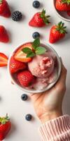 Scoop of strawberry sorbet surrounded by fresh berries on a neutral background in natural light photo