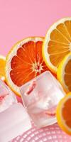 Refreshing citrus slices with ice cubes on a pink background create a vibrant and appetizing display photo