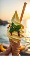Ice cream cone with chocolate drizzle and mint leaf near a lake at sunset photo