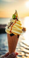 Delicious soft serve ice cream cone with caramel and chocolate syrup against a sunset background by the waterfront photo