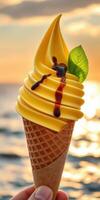 Delicious mango swirl ice cream cone enjoyed by the ocean during sunset photo