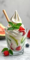 Delicious dessert with creamy soft serve, fresh raspberries, and mint leaves in a clear glass photo