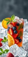 Refreshing summer beverage filled with fruits served cold on ice with mint garnish in a glass photo