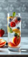 Refreshing fruit cocktail with berries and mint served in a tall glass on a marble surface photo