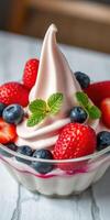 Delicious soft serve dessert topped with fresh strawberries, blueberries, and mint leaves in a glass bowl photo