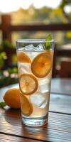 Refreshing lemon drink served in a tall glass with ice and fresh mint on a sunny table setting photo