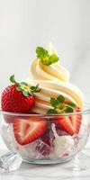 Delicious soft serve ice cream topped with fresh strawberries and mint leaves in a clear dessert bowl photo