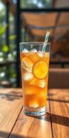 Refreshing orange beverage with ice served in a glass on a wooden table in a sunny cafe setting photo