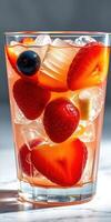 Refreshing summer drink with mixed fruits and ice in a clear glass under bright lighting photo