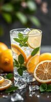 Refreshing lemonade with mint leaves and ice set on a dark surface alongside fresh lemons and slices photo