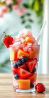 Refreshing fruit dessert with shaved ice served in tall glass photo