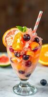Refreshing summer fruit dessert with ice, berries, and citrus served in a clear glass photo