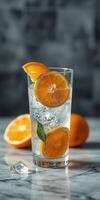 Refreshing citrus drink with ice and orange slices displayed on a marble surface photo