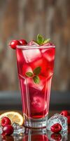 Refreshing red beverage garnished with mint and fruit served on a wooden table photo